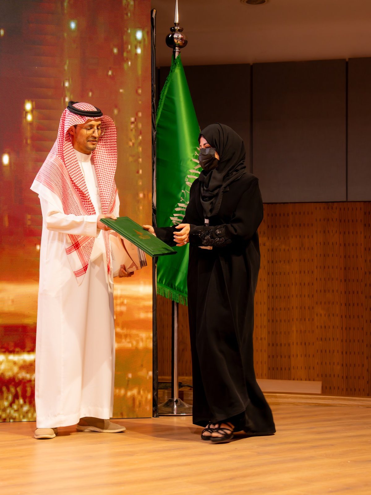 تكريم على المنصة بالعلم السعودي